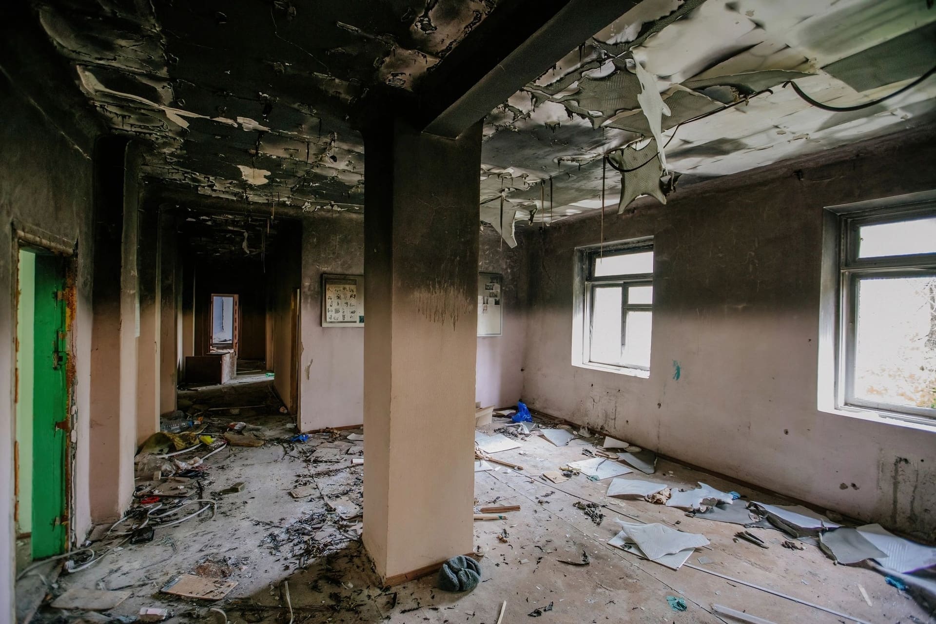 A fire-damaged hallway with charred walls and a collapsed ceiling