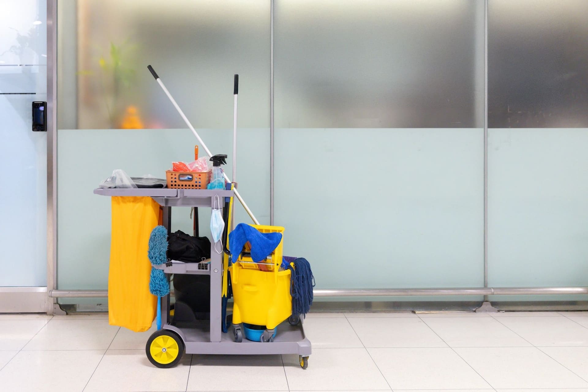 A janitorial cart with mops and buckets in an office lobby