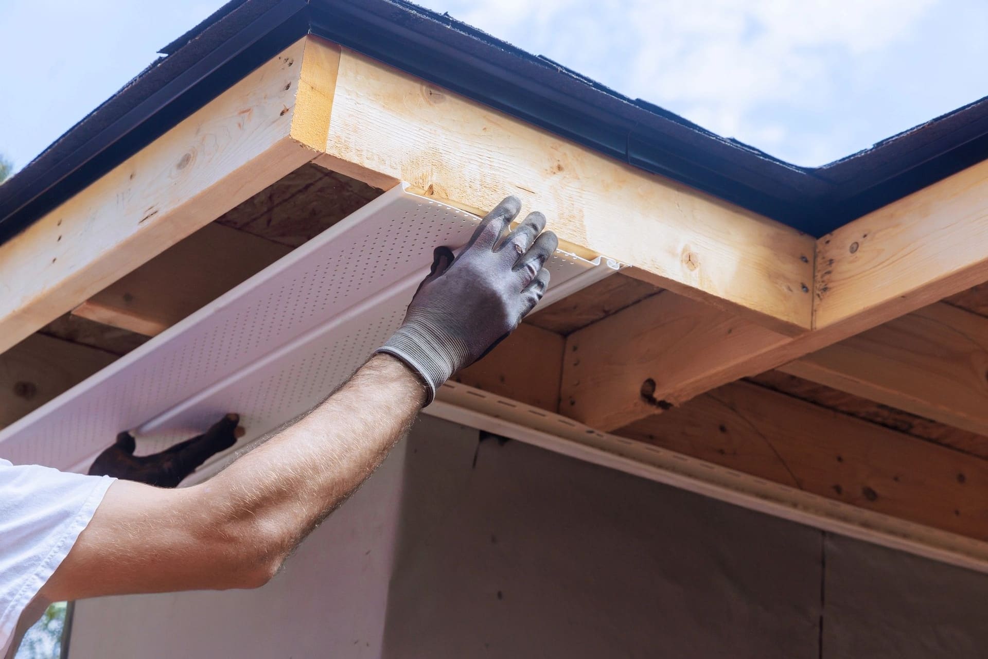 A soffit panel being fitted under the eave of a roof