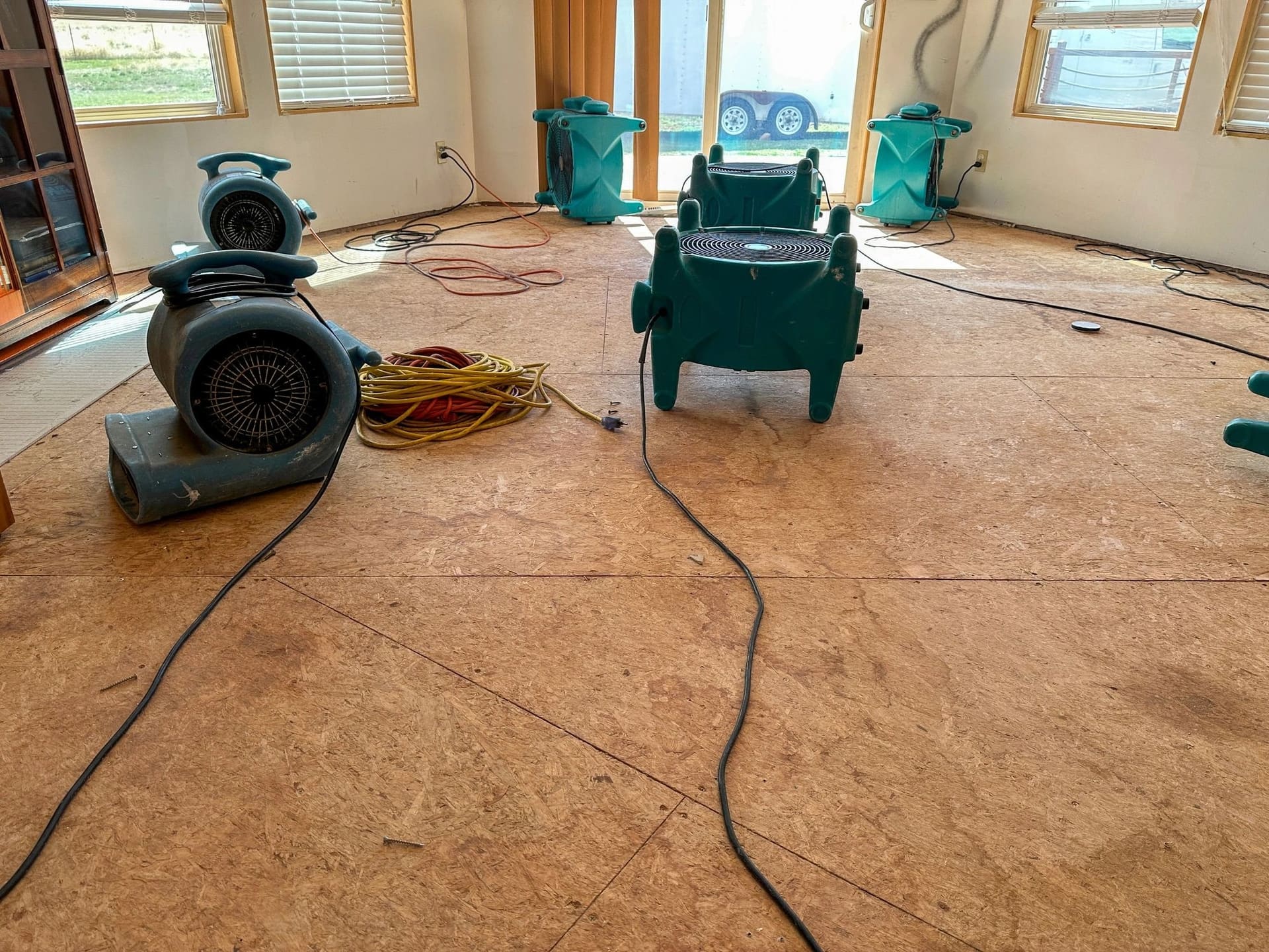 Air movers drying a room after water damage, carpet pulled up to the subfloor