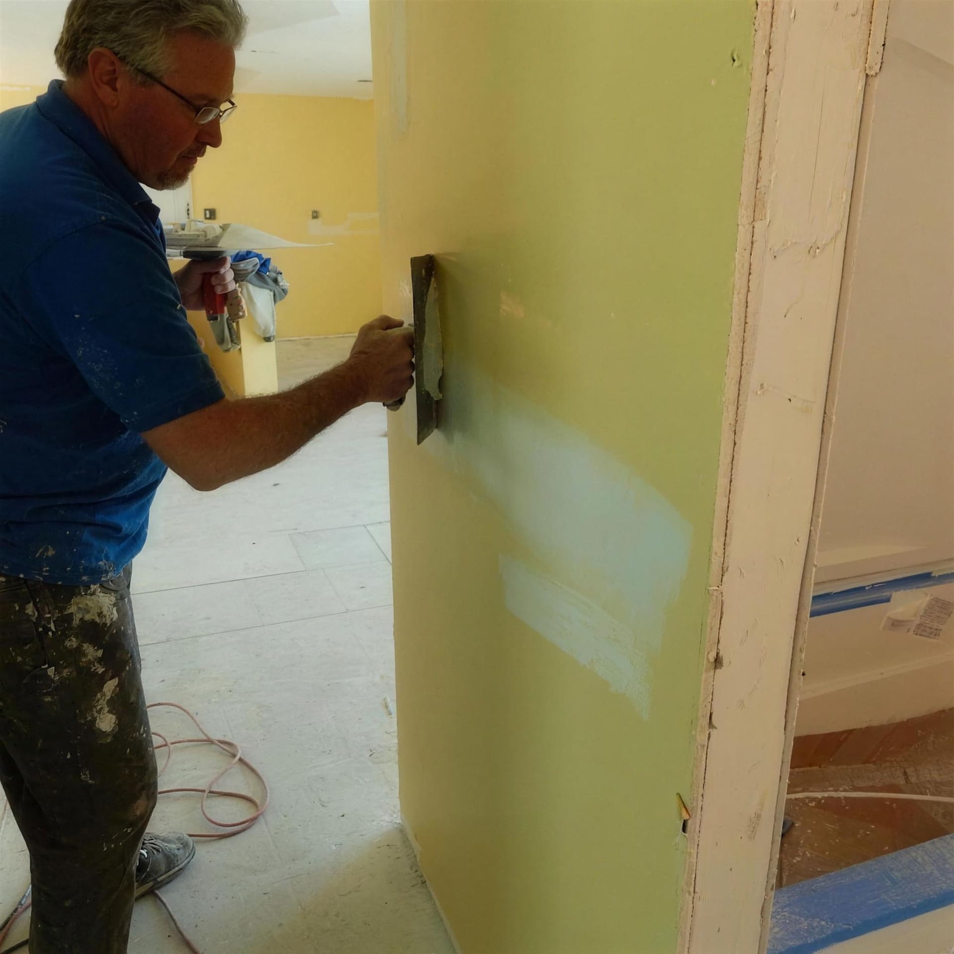 An ASJ technician finishing drywall during an interior remodel